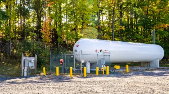 Citerne professionnelle de gaz propane installée à l'extérieur d'un établissement commercial français avec technicien effectuant une inspection